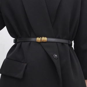 Close-up of slim black leather belt with gold metal buckle on a black suit blazer
