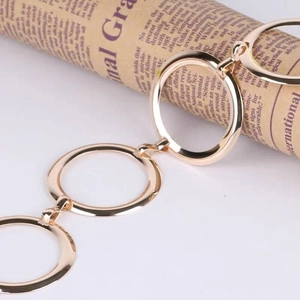 Detailed close-up of golden geometric metal ring waist chain on a newspaper prop