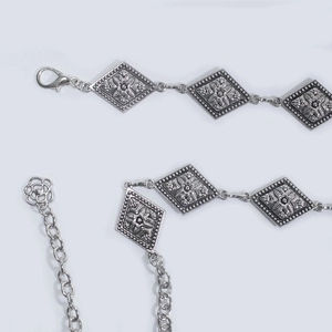 Détail de la chaîne de taille en métal argenté avec plaques gravées et pendentif rose