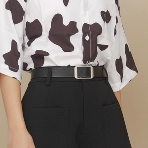 Close-up of minimalist black leather belt with silver rectangular buckle on trousers