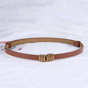 Detailed shot of a slim brown leather belt with a golden spiral buckle on white fabric