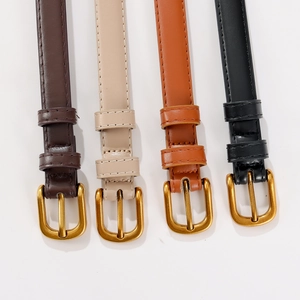 Gros plan de quatre ceintures fines en cuir (marron, beige, fauve, noir) avec boucles dorées