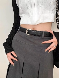 Close-up of a minimalist black leather belt with silver buckle on a pleated skirt