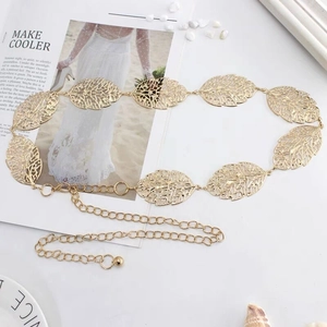 Detail of golden metal waist chain featuring hollow leaf pendants and adjustable link strap