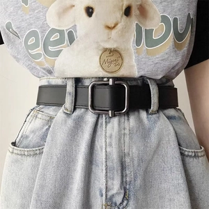 Close-up of black leather belt with silver-grey square metal buckle on denim jeans
