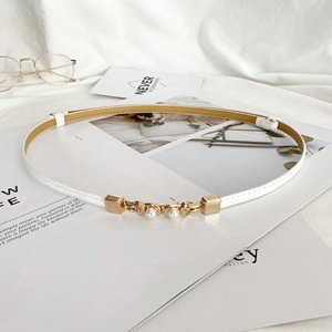 Close-up of thin white leather belt with gold metal buckle and elegant pearl details