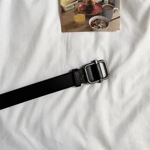 Macro shot of the durable silver square metal buckle on a classic black leather belt