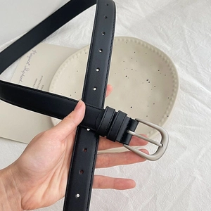 Close-up of slim black leather belt with silver horseshoe buckle and adjustable holes