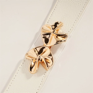 Detailed close-up of white leather belt with textured grain and elegant gold mushroom buckle