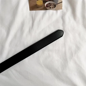 Close-up of black leather belt tail showing fine texture and precise edge stitching