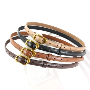 Détail de quatre fines ceintures en cuir beige, noir et marron avec boucles dorées vintage