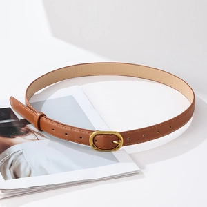 Detail of caramel brown PU leather belt with a golden oval buckle on a fashion magazine