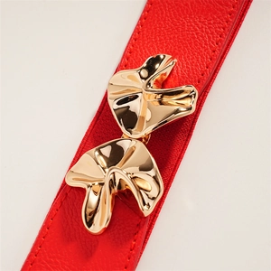 Close-up of elegant red elastic waist belt featuring a luxury wavy gold metal buckle
