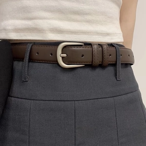 Classic dark brown leather belt with silver matte buckle on grey pleated skirt