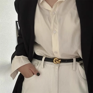 Minimalist black slim leather belt for women with gold twist buckle on blazer and pants