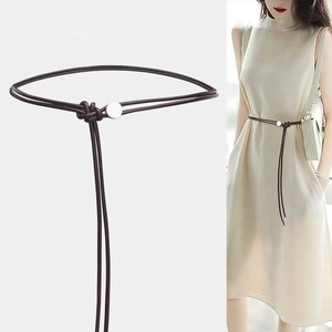 Détail du cordon de taille en cuir marron avec boucle en métal argenté et design noué