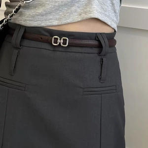 Close-up of a brown slim PU leather belt with silver square buckle on grey suit skirt