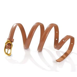 Détail d'une ceinture en cuir marron avec boucle dorée montrant les coutures et la texture