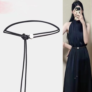 Détail d'une ceinture minimaliste en corde tressée noire avec perle argentée sur robe