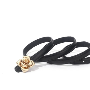 Elegant thin black PU leather belt with a 3D golden rose flower buckle on white background