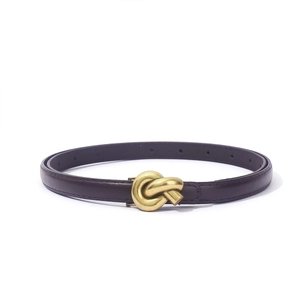 Detailed macro view of the elegant golden knot metal buckle on a slim PU leather belt