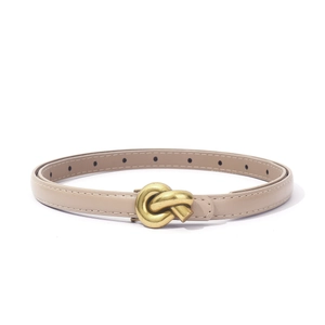 Detail of beige skinny belt with golden twist buckle and neat stitching on white background