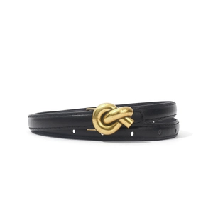 Detailed view of women's slim PU belt with golden metal knot buckle and black leather strap