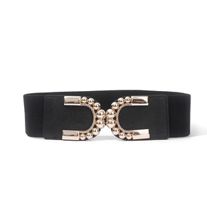 Détail de ceinture élastique noire avec boucle dorée en forme de U et perles