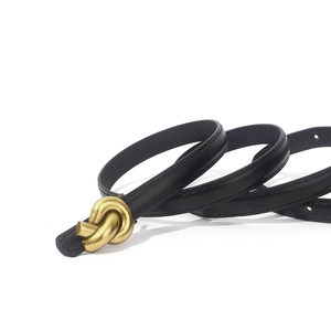 Detail view of black leather belt with a vintage gold knotted metal buckle and fine stitching