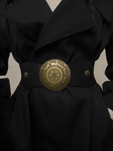 Close-up of vintage bronze circular buckle with floral relief on wide black waist belt