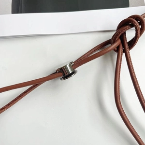 Macro d'une fine ceinture en cuir marron avec boucle argentée et détails noués