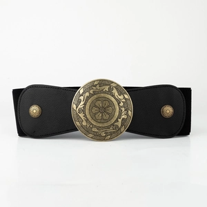 Close-up of vintage bronze buckle with floral engraving on a black wide elastic belt