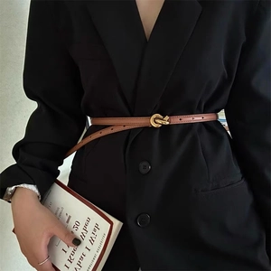 Close-up of a slim brown leather belt with a gold knot buckle on a black blazer jacket
