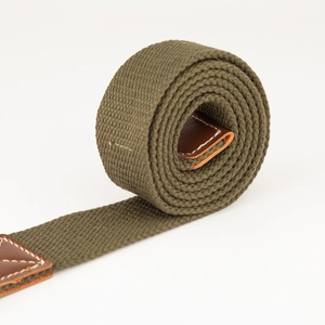 Detailopname van olijfgroene canvas riem met bruine lederen versterking en wit stiksel