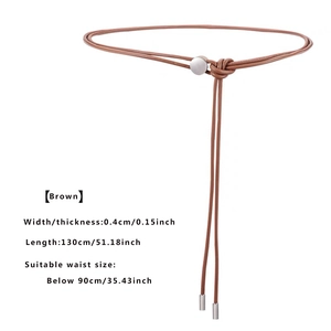 Détail de la fine ceinture en similicuir marron avec boucle argentée et design noué