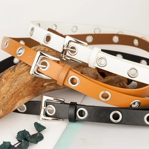 Close-up of three faux leather belts in black white and brown with silver eyelets