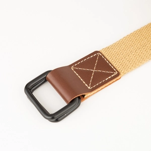 Detail van canvas riem met bruin lederen uiteinde en zwarte dubbele D-ring metalen gesp