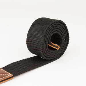 Detail van zwarte canvas riem met bruin lederen uiteinde en duurzame witte stiksels