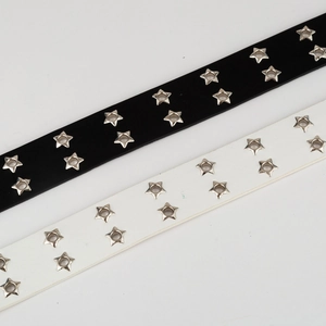 Detailed view of punk style black and white leather belts with star-shaped silver eyelets