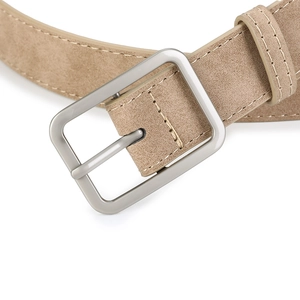 Close-up of beige matte suede belt with silver brushed metal buckle and contrast stitching