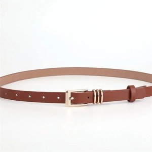 Detail of slim brown faux leather belt featuring a polished gold rectangular buckle