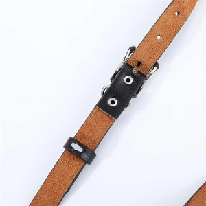 Détail d'une ceinture en cuir grainé noir avec boucle en métal argenté et œillets en métal