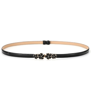 Detail of elegant black patent leather skinny belt featuring enamel floral buckle for dresses