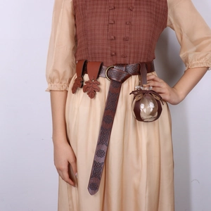Detail of medieval leather belt with Celtic embossing and a hanging glass potion bottle