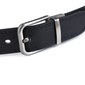 Gros plan sur la boucle en métal argenté brossé et la ceinture en cuir noir surpiqué