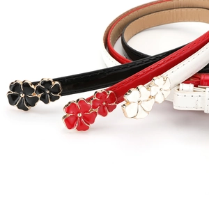 Detail of three patent leather belts in black red and white with floral enamel buckles