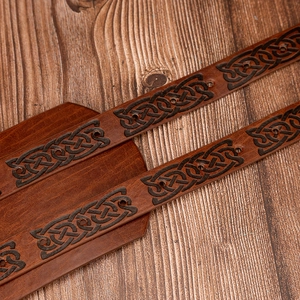 Macro detail of brown leather belt with embossed Celtic knot and precision stitching
