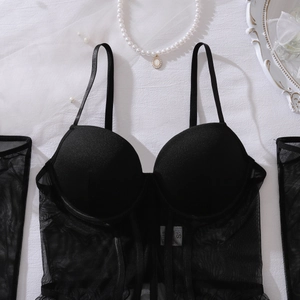 Détail à plat d'un corset en maille noire avec bonnets en satin et manches assorties