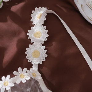 Detailed close-up of white daisy floral embroidery on mesh strap of sexy lingerie set