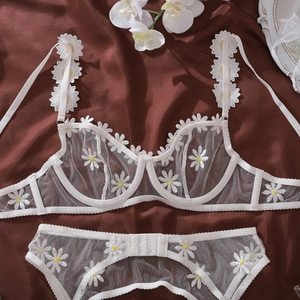 Detailed macro view of delicate white mesh lace with embroidered yellow daisy patterns